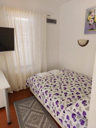 a small bedroom with a bed with a flowered blanket at Villa Lyudmila in Utjeha