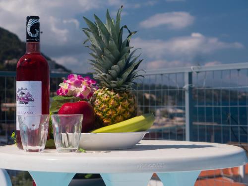 a bottle of wine and a bowl of fruit on a table at Corfu Star Apartments in Benitses