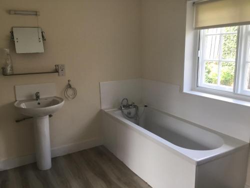 a bathroom with a bath tub and a sink at Thatched Cottage Wix in Wix