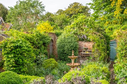 a garden with a fountain in the middle at Extraordinary 15th Century timber framed cottage in famous Medieval village - The Tryst in Lavenham