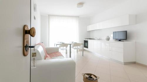 a white living room with a chair and a kitchen at Residenza Excelsior in Vasto