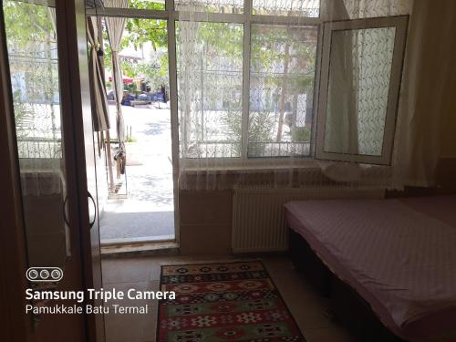 a bedroom with a bed and a window and a door at Pamukkale Batu Termal in Pamukkale