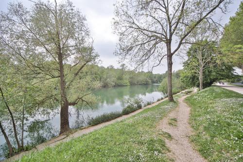 um caminho junto a um rio com árvores em Blue Nights Appartements 71 em Chennevières-sur-Marne