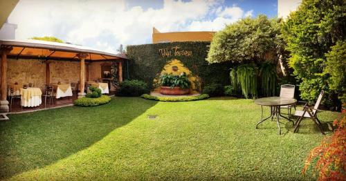 a garden with a table and a large painting on the wall at Hostal Villa Toscana in Guatemala