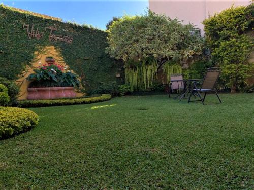a yard with a garden with a table and chairs at Hostal Villa Toscana in Guatemala