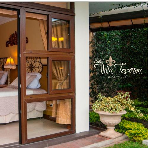 a room with a glass door with a bed and a vase at Hostal Villa Toscana in Guatemala
