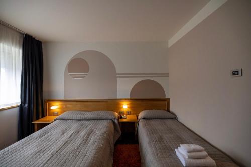 a hotel room with two beds and a desk at Hotel Europa Belluno in Belluno