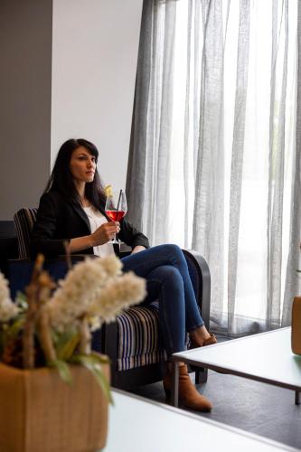 a woman sitting in a chair holding a glass of wine at Hotel Europa Belluno in Belluno