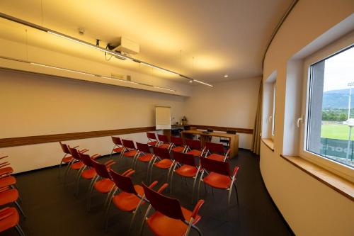 a conference room with red chairs and a large window at Hotel Europa Belluno in Belluno