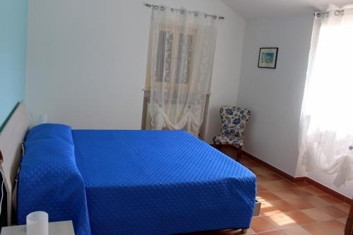 a bedroom with a blue bed and a chair at L'ulivo e lo scoiattolo in Marina Palmense