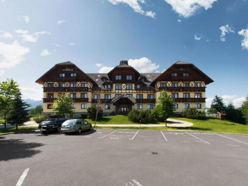 a large building with cars parked in a parking lot at TatryView Apartments by KingDubaj in Veľká Lomnica