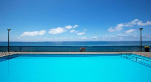 a swimming pool with the ocean in the background at Atlantic Gardens Beach - atlanticgardensbeach com in Funchal