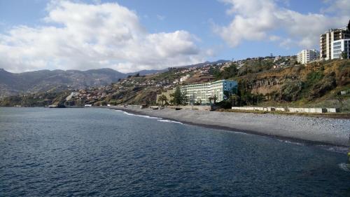 a view of a beach with buildings and mountains at Atlantic Gardens Beach - atlanticgardensbeach com in Funchal