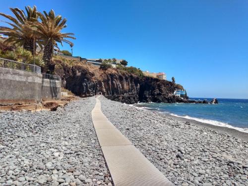 a path on a rocky beach next to the ocean at Atlantic Gardens Beach - atlanticgardensbeach com in Funchal