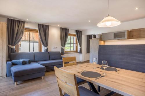 Una sala de estar con una mesa y un sofá azul. en Lechnerhof Fane Alm, en Valles
