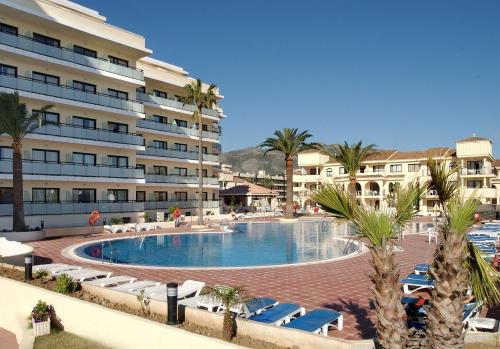 a large hotel with a swimming pool and palm trees at Hotel Puente Real in Torremolinos