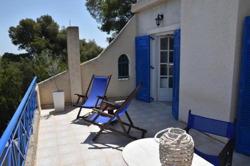 two blue chairs on a patio with a table at Villa Iokasti (sea view) in Pefkali
