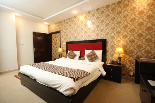 a bedroom with a large bed with a red headboard at Safari Club 4 in Rawalpindi
