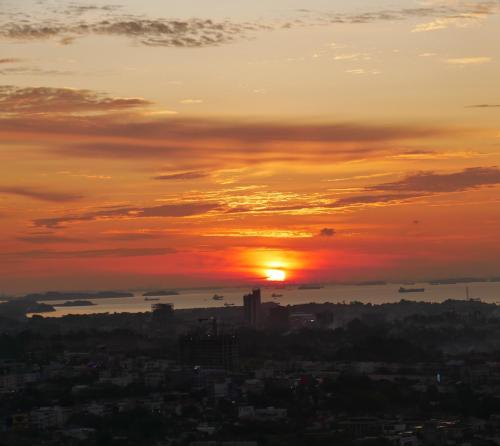 a sunset with the sun setting over a city at Meisterstadt Pollux Habibie in Batam Center