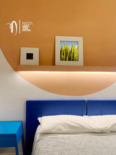 a bedroom with a blue bed and two pictures on a shelf at Hotel Nizza Creative Hotel in Rimini