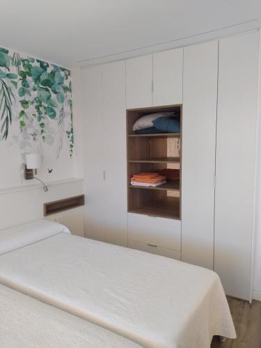 a white bedroom with a bed and cabinets at pleno centro nuevo parking in León