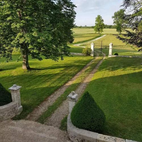 a path in a field with a tree and a house at Domaine et Manoir du Picaud in Monestier