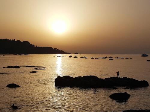a person standing on a rock in the water at sunset at Sole Mare B&B in Giardini Naxos