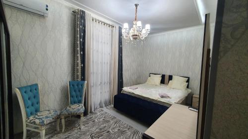 a bedroom with a bed and two chairs and a chandelier at Fayzli GuestHouse in Tashkent