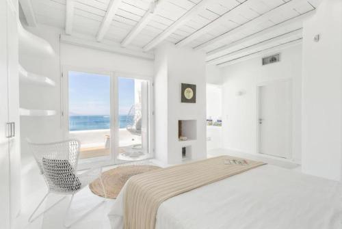 Villa Goddess by Whitelist Mykonos في أغيوس يوانيس ميكونوس: غرفة نوم بيضاء مع سرير وإطلالة على المحيط
