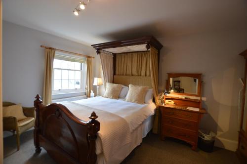 a bedroom with a bed and a dresser and a mirror at Chantry Hotel in Bury Saint Edmunds