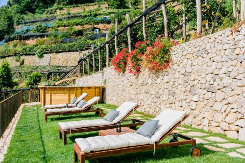 a group of chaise lounges on the grass near a stone wall at Villa Le Murelle in Tramonti