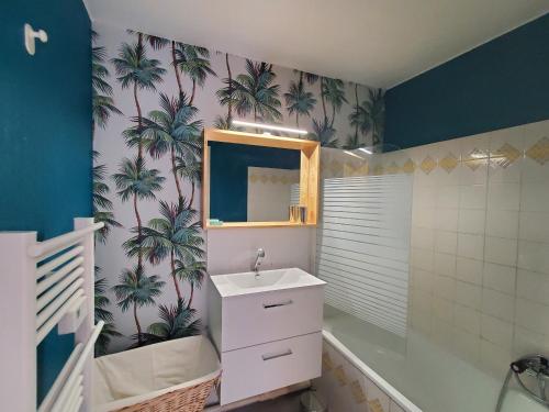 La salle de bains est pourvue d'un lavabo et d'un miroir recouvert de palmiers. dans l'établissement MIOUGRANO T1 Bis 30m2 4 Personnes 200 m de la Plag, à Fréjus