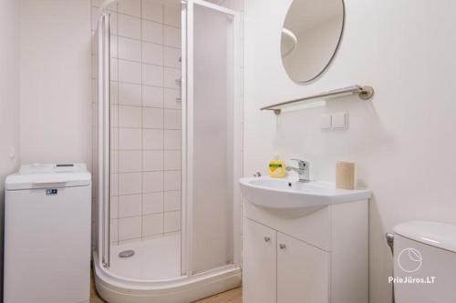 un bagno bianco con doccia e lavandino di Apartamentai Malūno vilose a Palanga