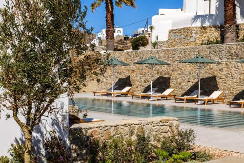 a swimming pool with lounge chairs and umbrellas at Camarades Mykonos in Ano Mera