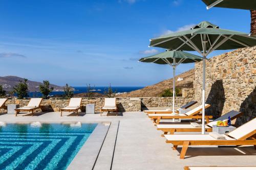 a pool with chairs and umbrellas next to a resort at Camarades Mykonos in Ano Mera