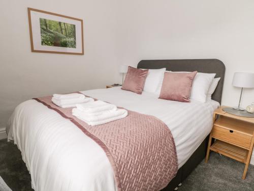a bedroom with a bed with white sheets and pink pillows at Ermysted's Cottage in Skipton