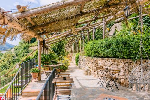 a patio with tables and chairs and a stone wall at Villa Le Murelle in Tramonti