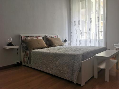 a white bedroom with a bed and a window at Appartamento Diego in Milan
