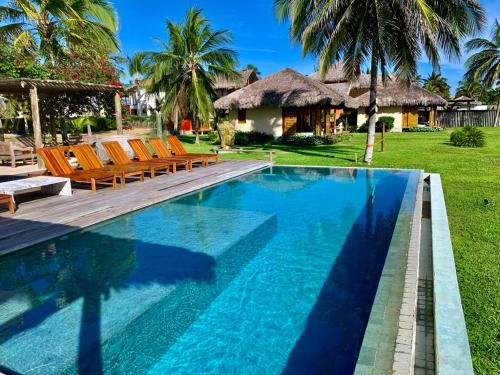 a swimming pool with chairs and a house at Vila Ybytu Eco Resort in Itarema