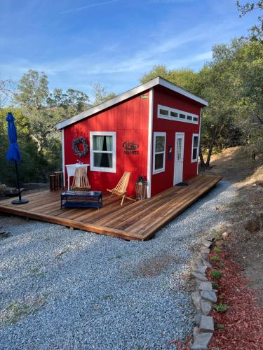 a red tiny house with a wooden deck at McMillan Ranch Yosemite in Coarsegold