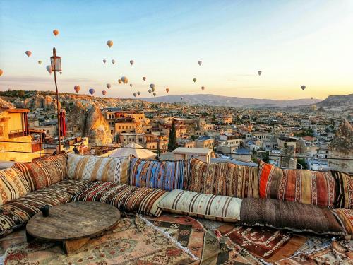 a couch on top of a city with hot air balloons at Cappadocia Cave Lodge in Göreme