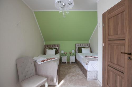 a bedroom with two beds and a chair and a chandelier at Bükki Villa in Bükkszék
