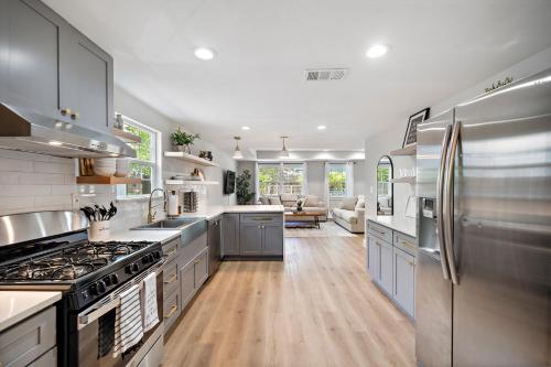 a large kitchen with stainless steel appliances and wooden floors at Blue Bungalow In Houston Heights! Walkable to Popular Bars in Houston