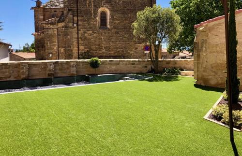 a yard of green grass in front of a church at Palacio Condes de Cirac in Villalba de Rioja