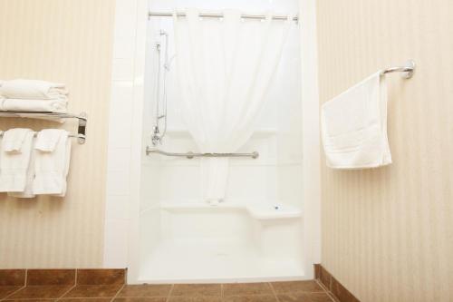 a bathroom with a tub and a shower with towels at Pomeroy Inn & Suites at Olds College in Olds