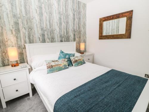 a bedroom with a white bed and a mirror at Harbour Hideaway in Looe