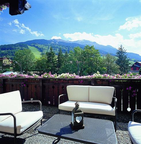 two chairs and a table on a patio with a view at Hotel Baita Dei Pini in Bormio