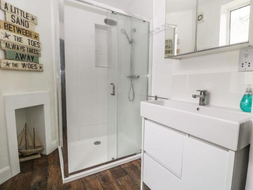 a white bathroom with a shower and a sink at Harbour Hideaway in Looe
