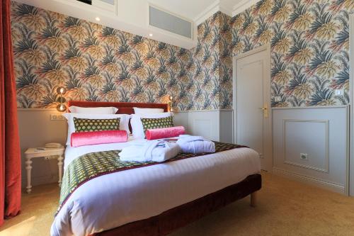 a bedroom with a large bed with colorful pillows at Hôtel Petit Palais in Nice