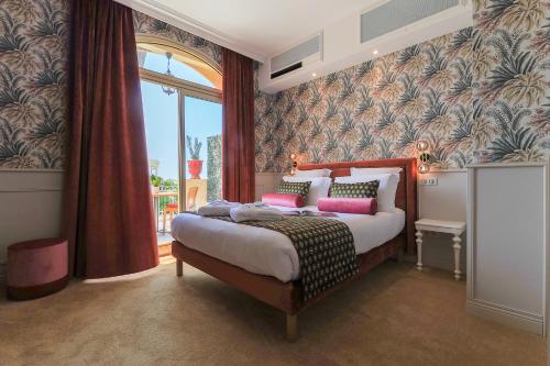 a bedroom with a large bed and a large window at Hôtel Le Petit Palais in Nice